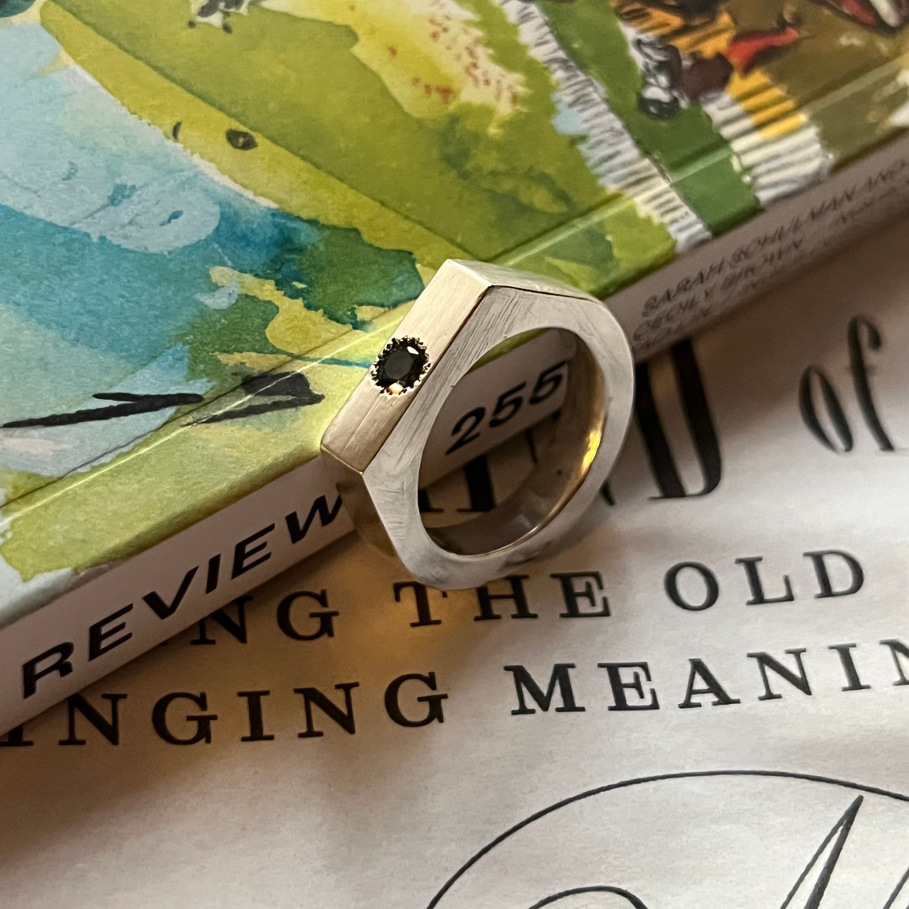 Silver ring with a diamond on a book with illustrations